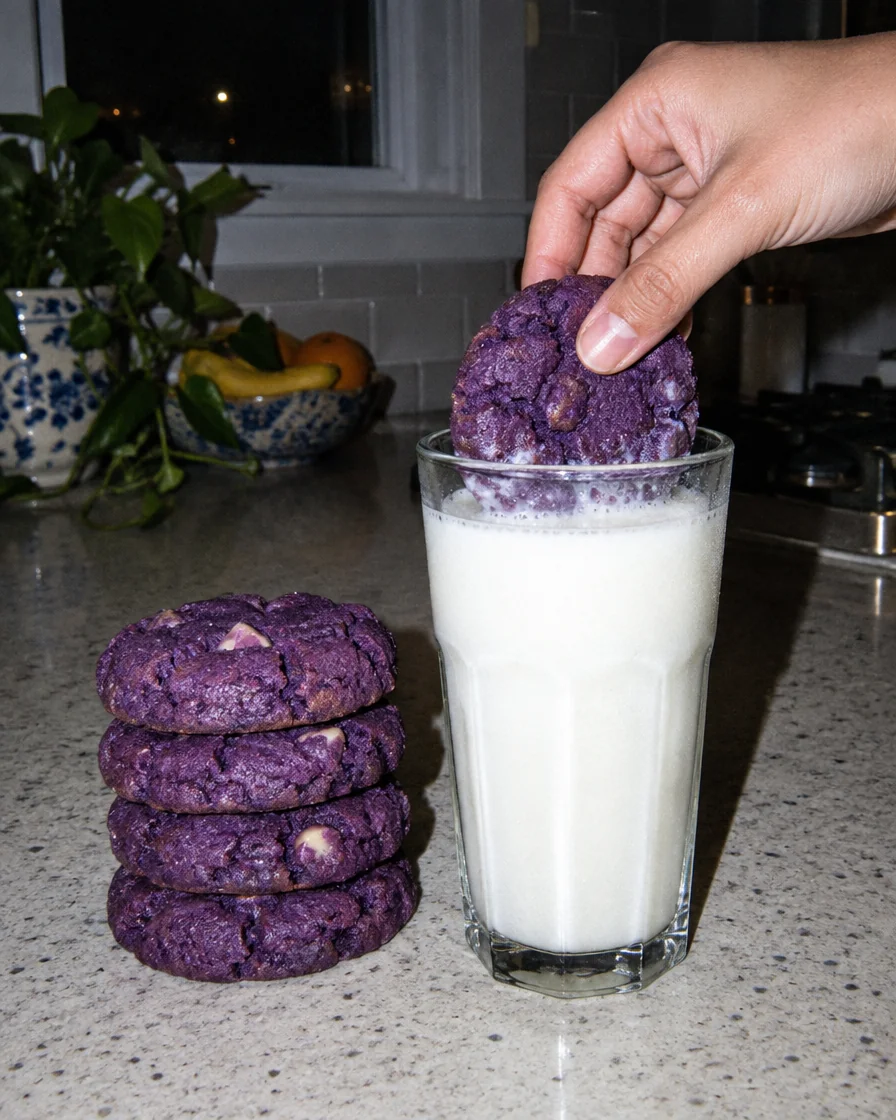 A stack of chewy ube cookies next to a glass of milk