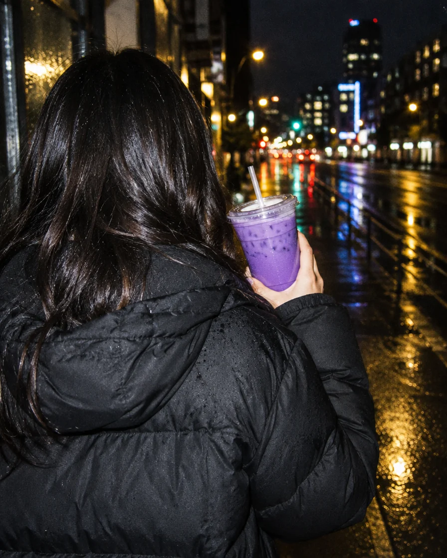 Becher Ube Milk Tea in der Hand, abends auf der Straße