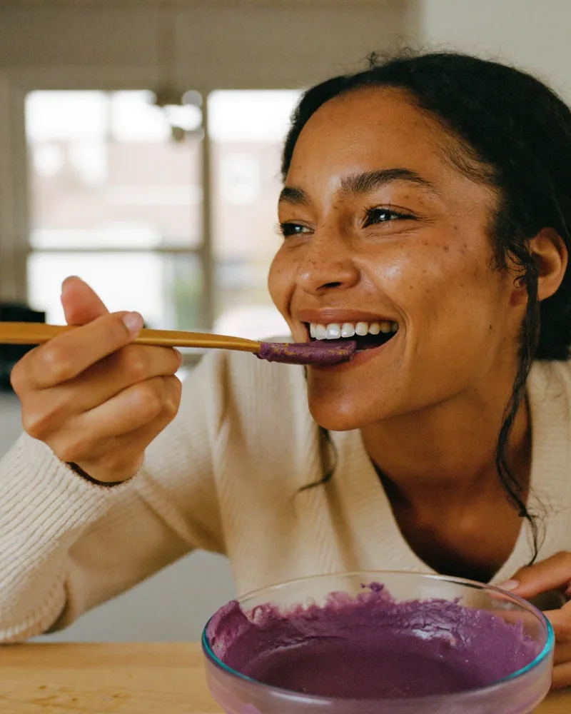Femme qui goûte de l'ube violet à la cuillère