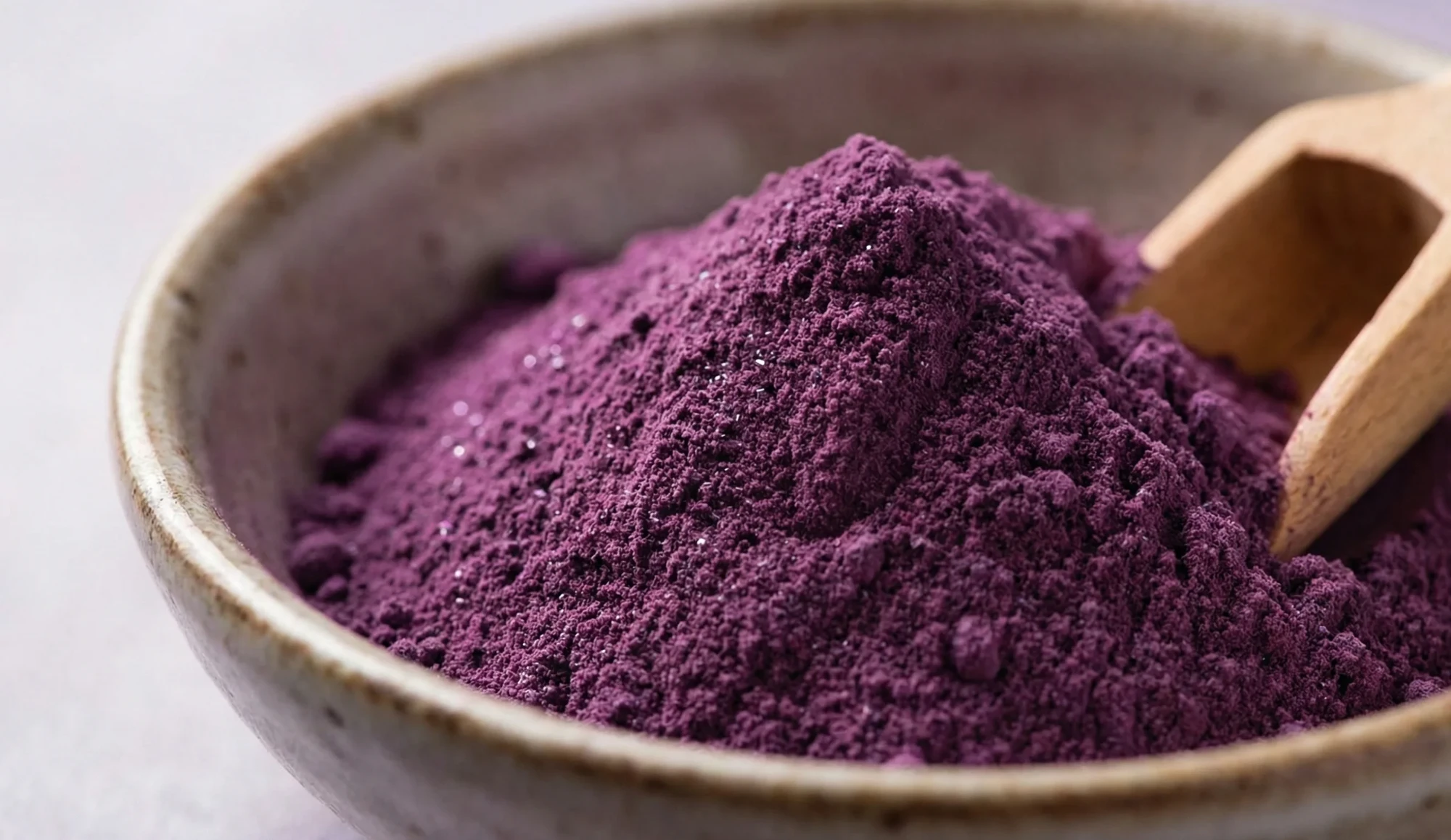 Bowl of 100% pure ube powder with a wooden scoop